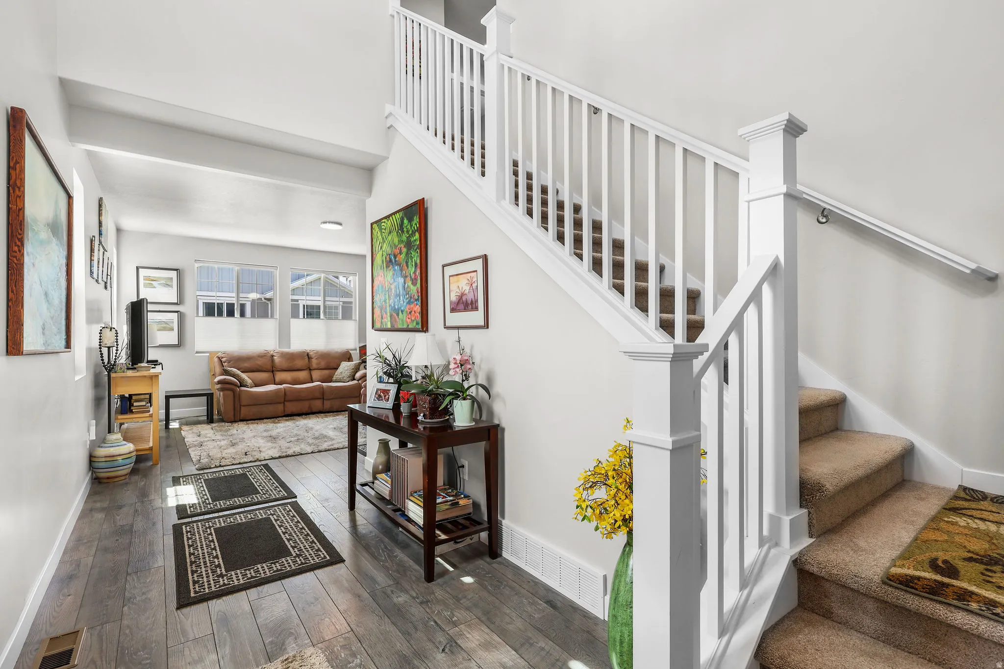 Entryway featuring light wood-finish flooring, white trim, and a carpeted staircase with white balusters