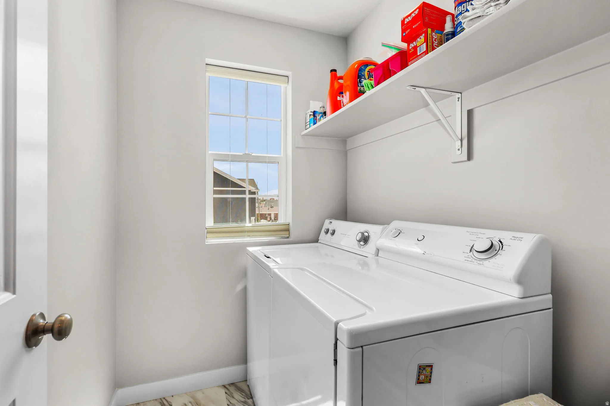 Dedicated laundry area featuring a window, built-in shelving, and wood-finish flooring