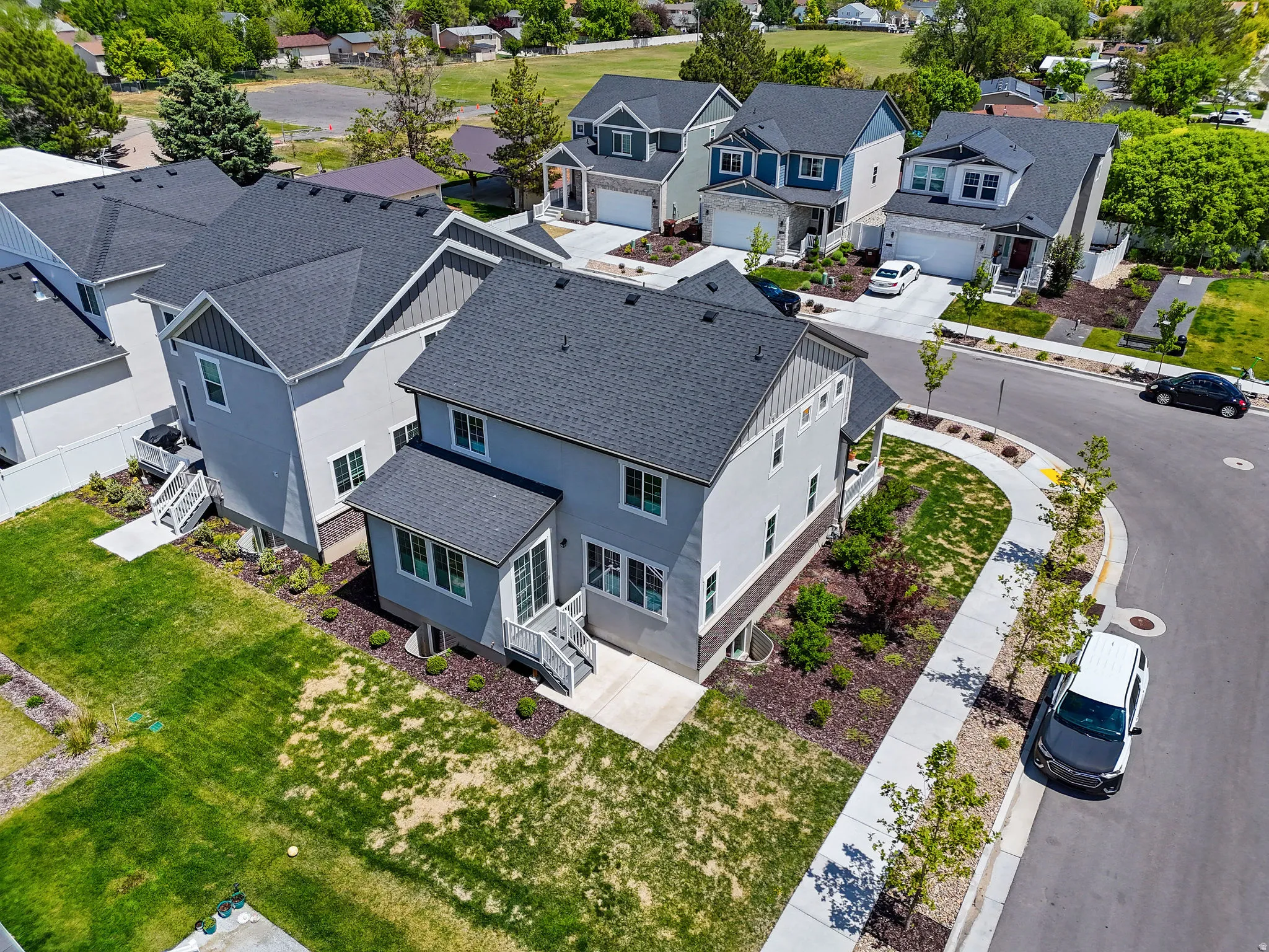 Contemporary multi-story residence featuring light gray siding with dark trim accents, a prominent front-facing gable, and a dark shingled roof