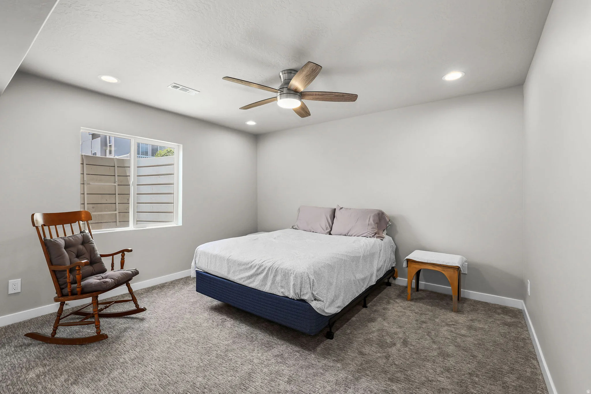 Carpeted room with a ceiling fan, recessed lighting, and a white window frame with horizontal louvered blinds
