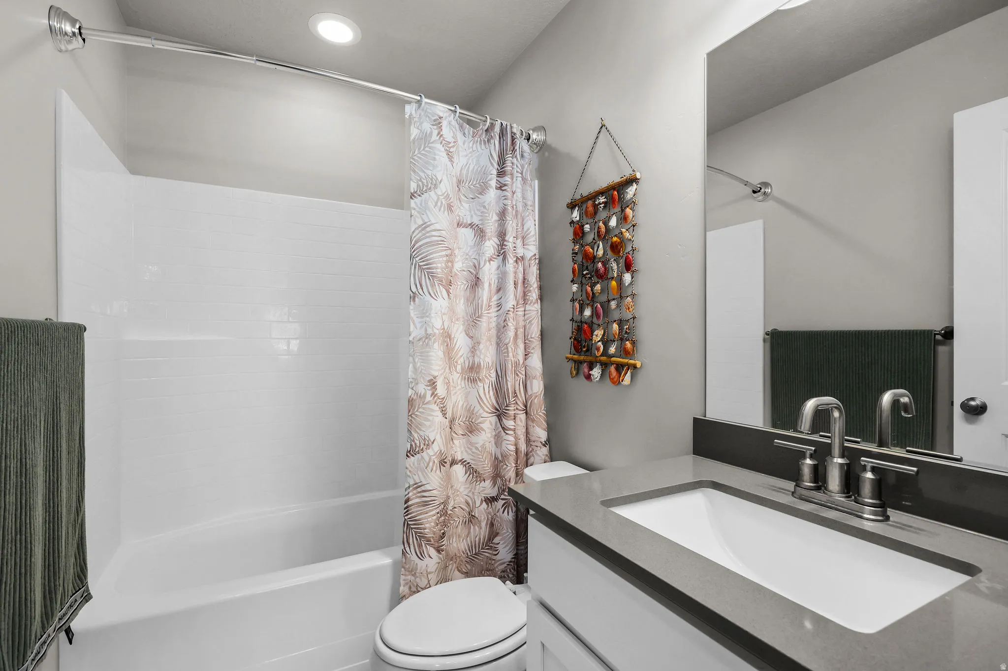 Bathroom featuring a built-in tub and shower combination with a white subway tile surround, recessed lighting, a vanity with a rectangular undermount sink, and a gray countertop