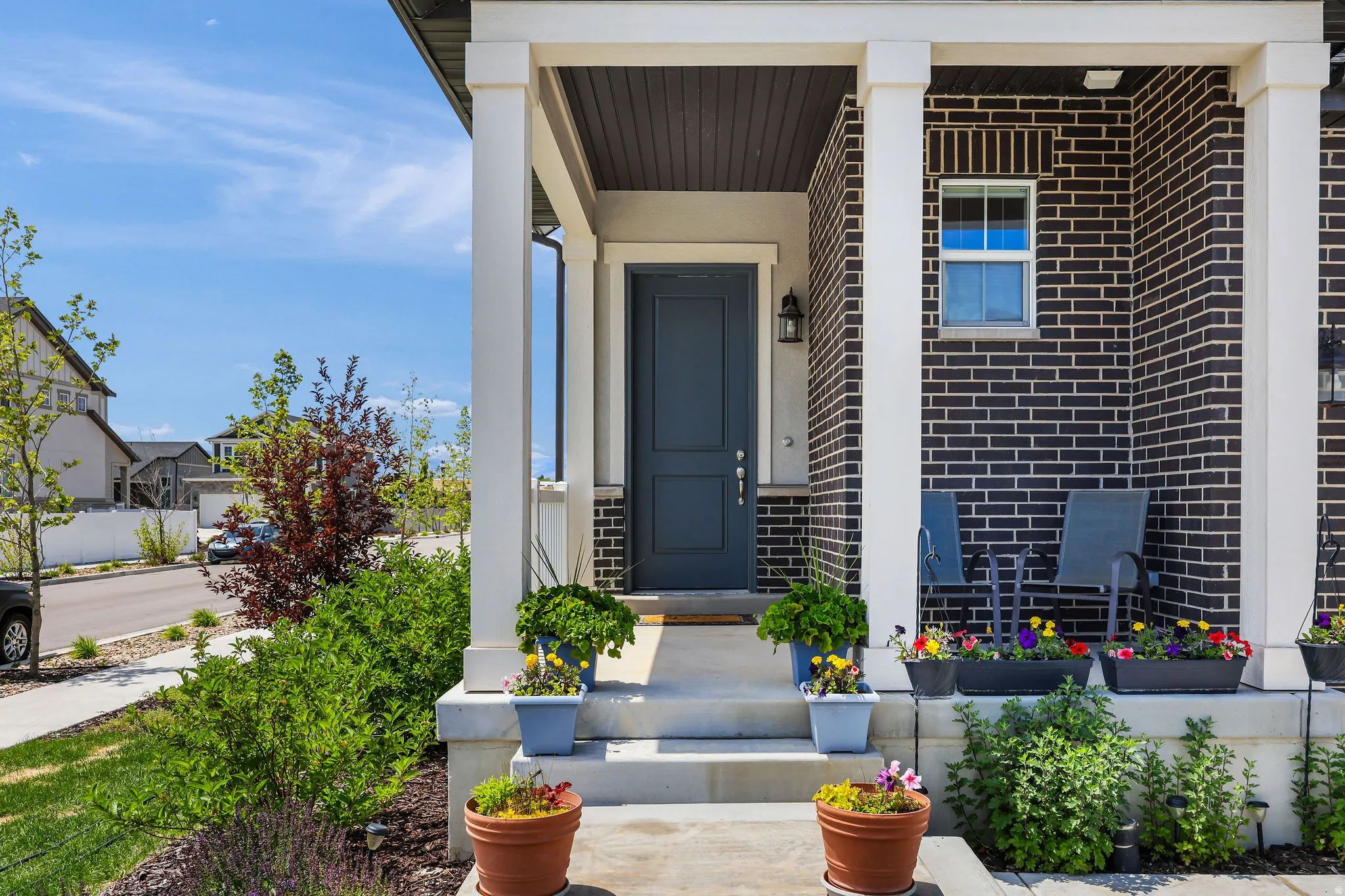 Exterior featuring a dark brick facade, a covered porch with white columns, and a deep blue entry door with transom window