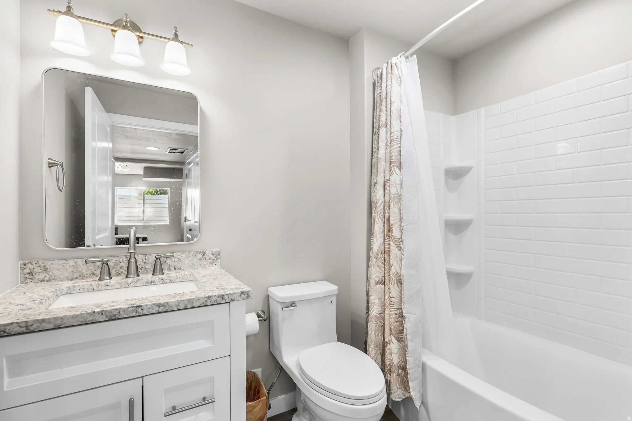 Bathroom featuring a white vanity with a light-colored speckled countertop, an undermount sink, and brushed nickel fixtures