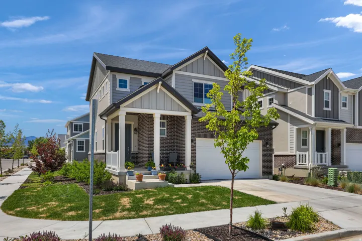 Contemporary multi-story residence featuring a covered front porch, a two-car garage, and a brick and siding exterior