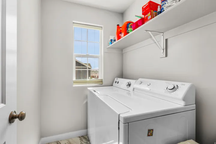 Dedicated laundry area featuring a window, built-in shelving, and wood-finish flooring