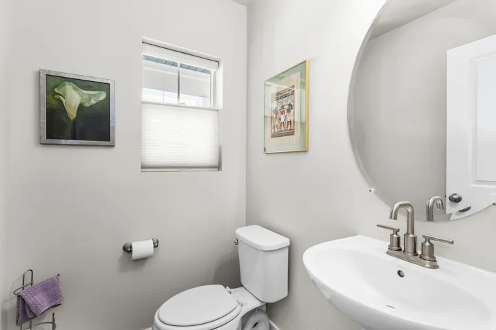Contemporary powder room featuring a pedestal sink, brushed nickel faucet, and a large circular mirror