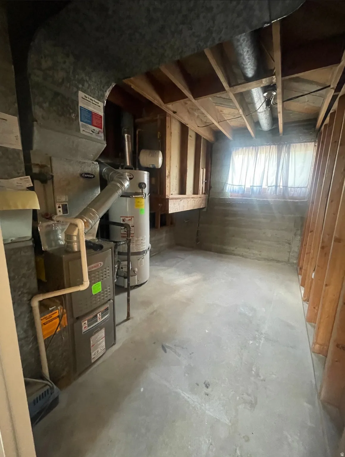 Utility room featuring a furnace, water heater, exposed ductwork, and concrete flooring