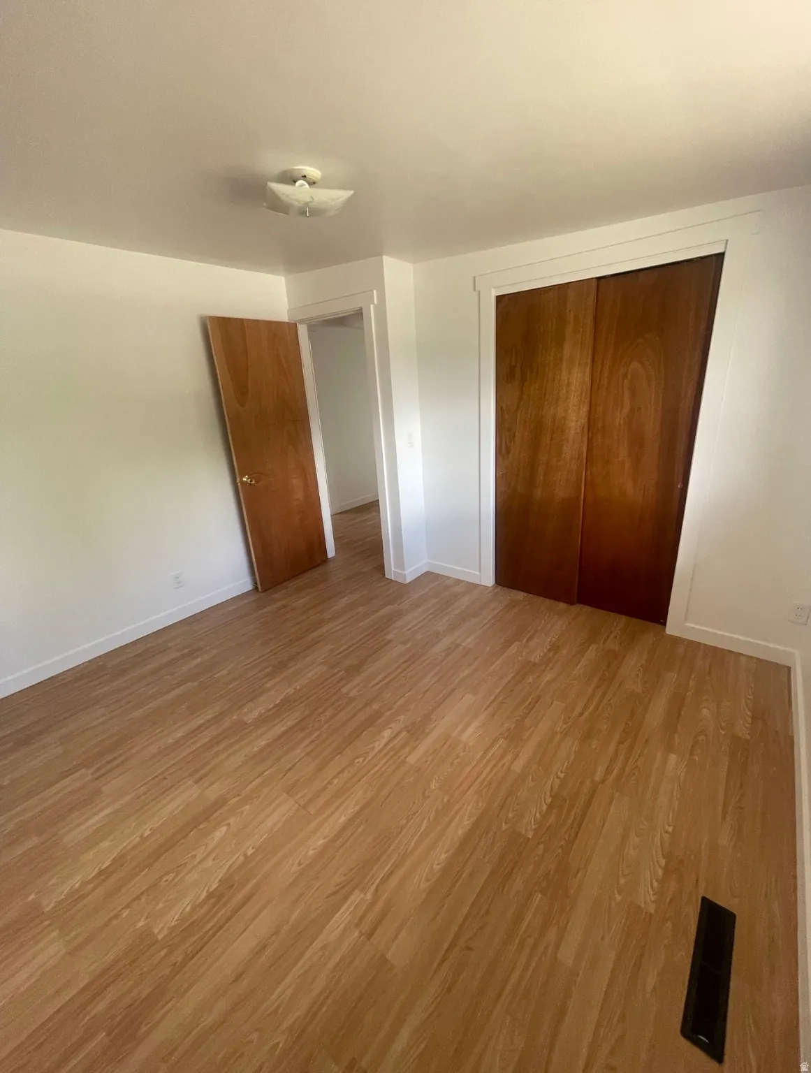 Room featuring wood-finish flooring, white baseboards, and a semi-flush ceiling light fixture