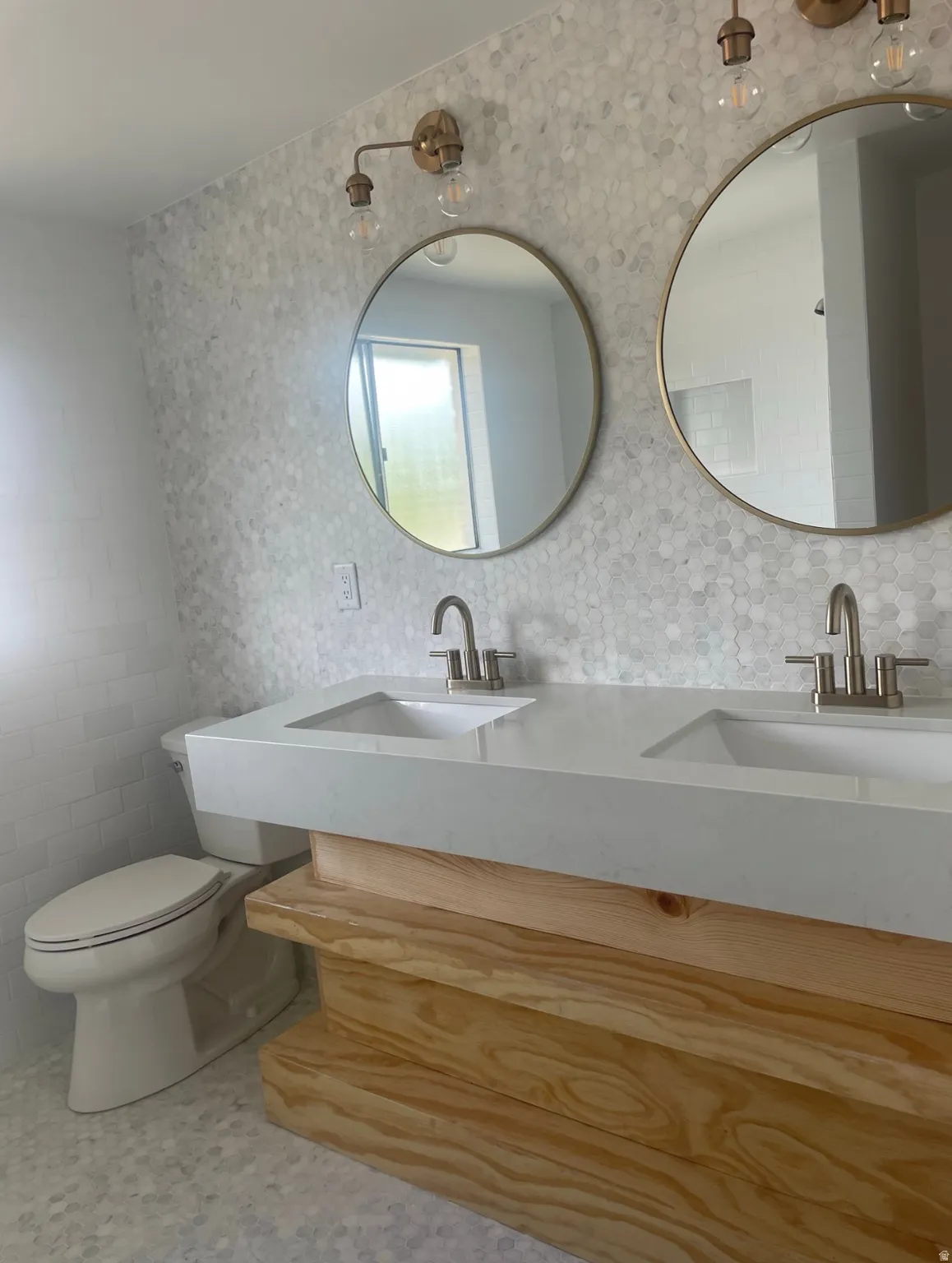 Dual basin vanity featuring a light wood-finish base and integrated white sinks