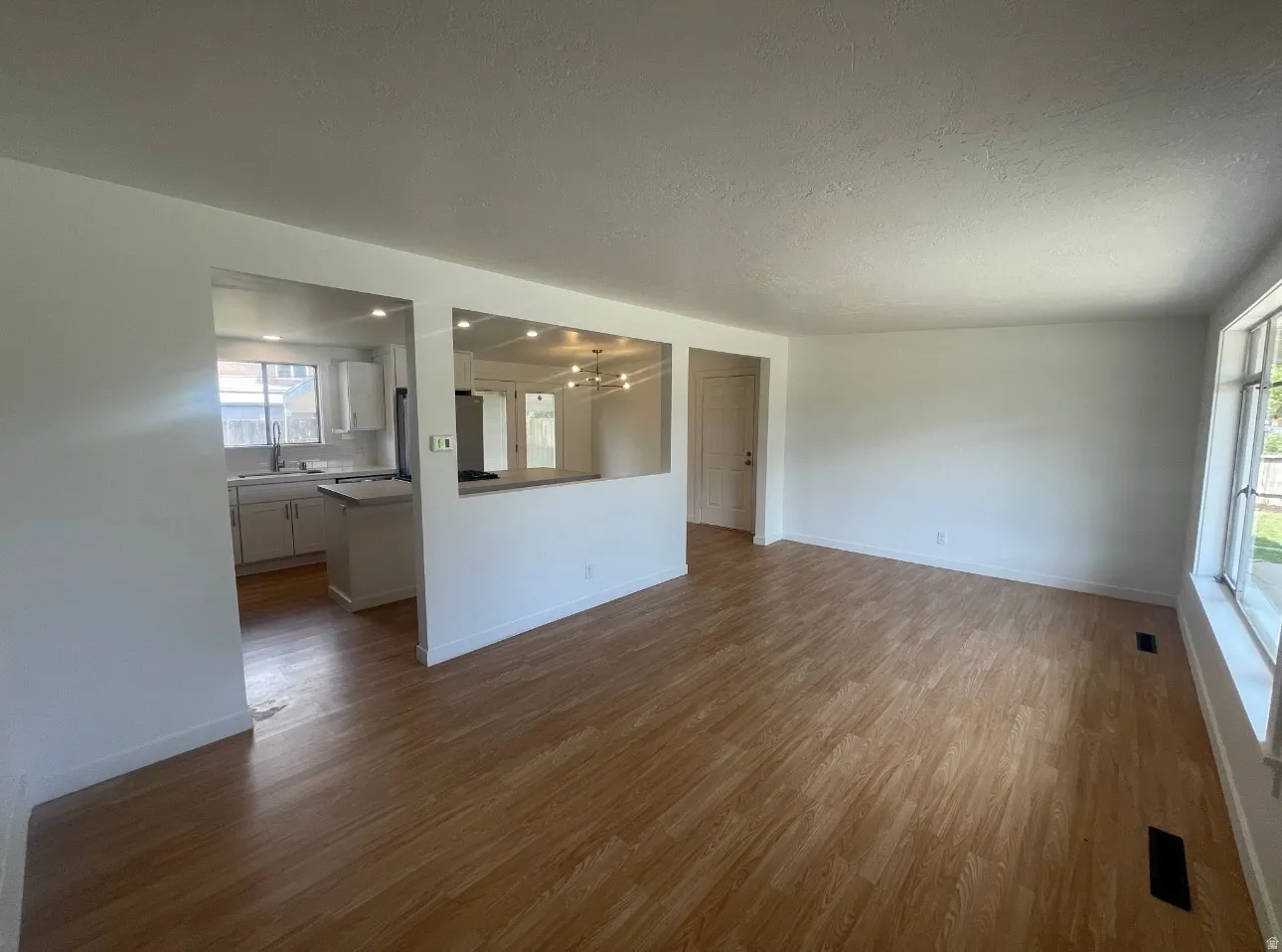 Open-concept living area featuring wood-finish flooring and white walls
