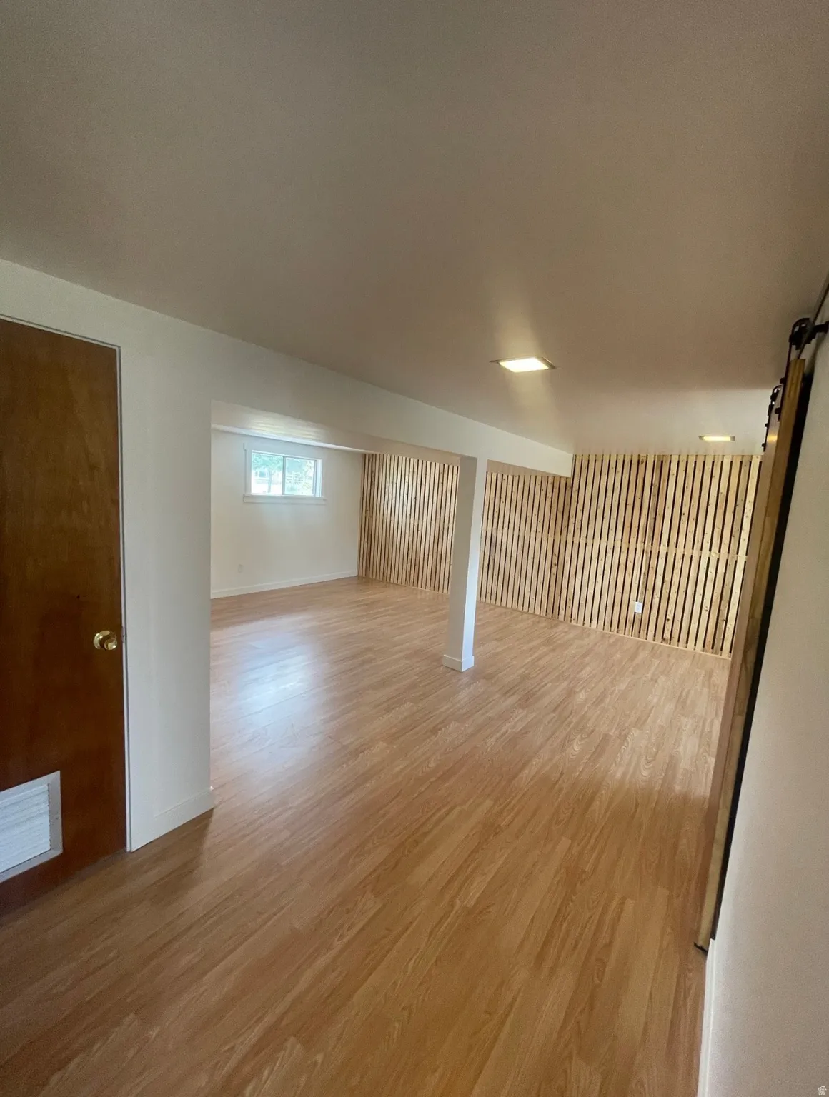 Spacious room featuring wood-finish flooring and recessed lighting
