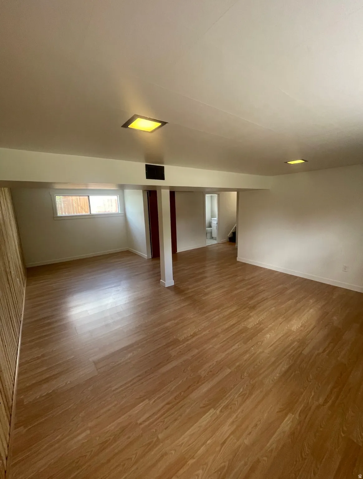 Spacious room featuring wood-finish flooring, recessed lighting, and white walls