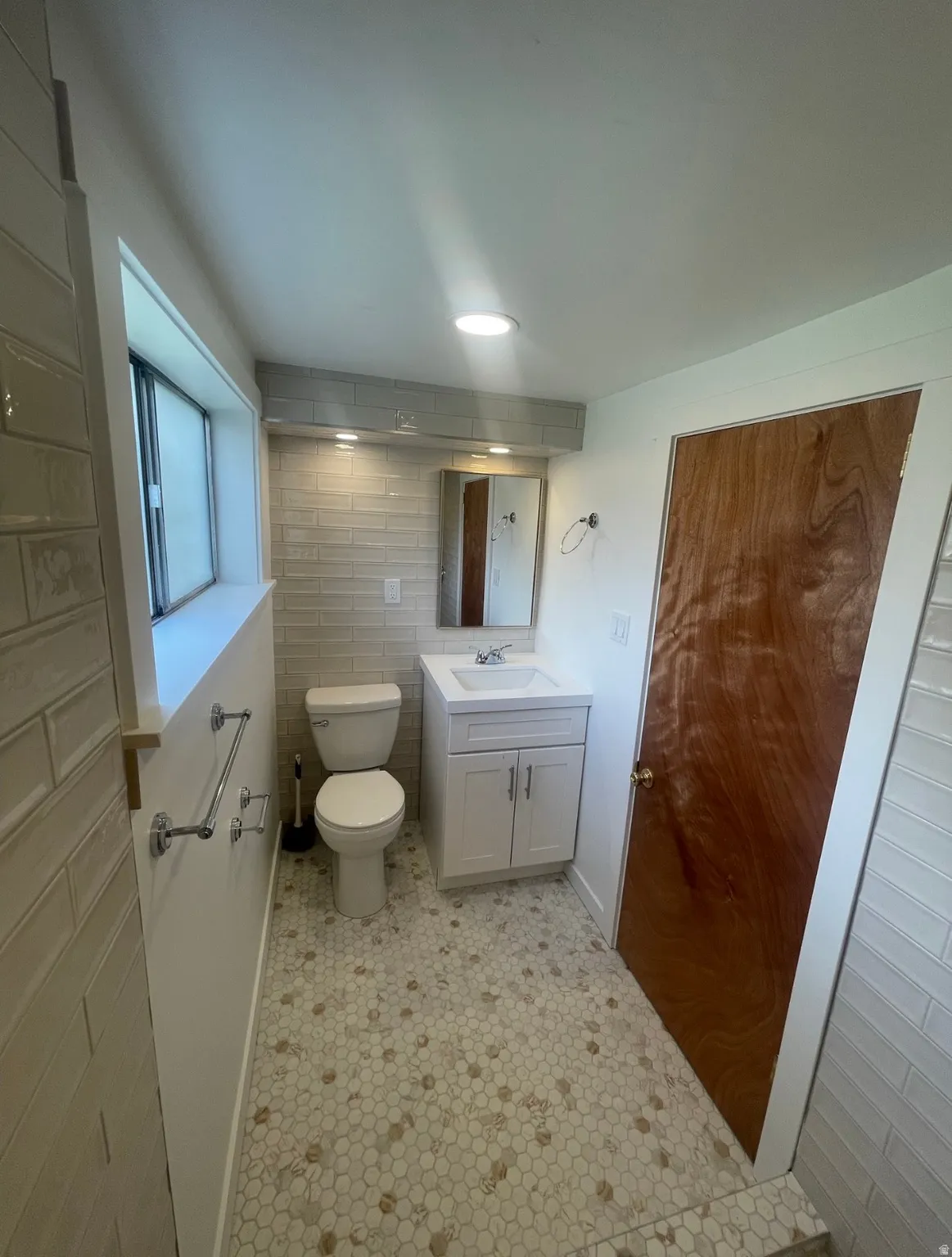 Contemporary bathroom featuring hexagonal mosaic floor tiles, a white vanity with integrated sink, and a toilet