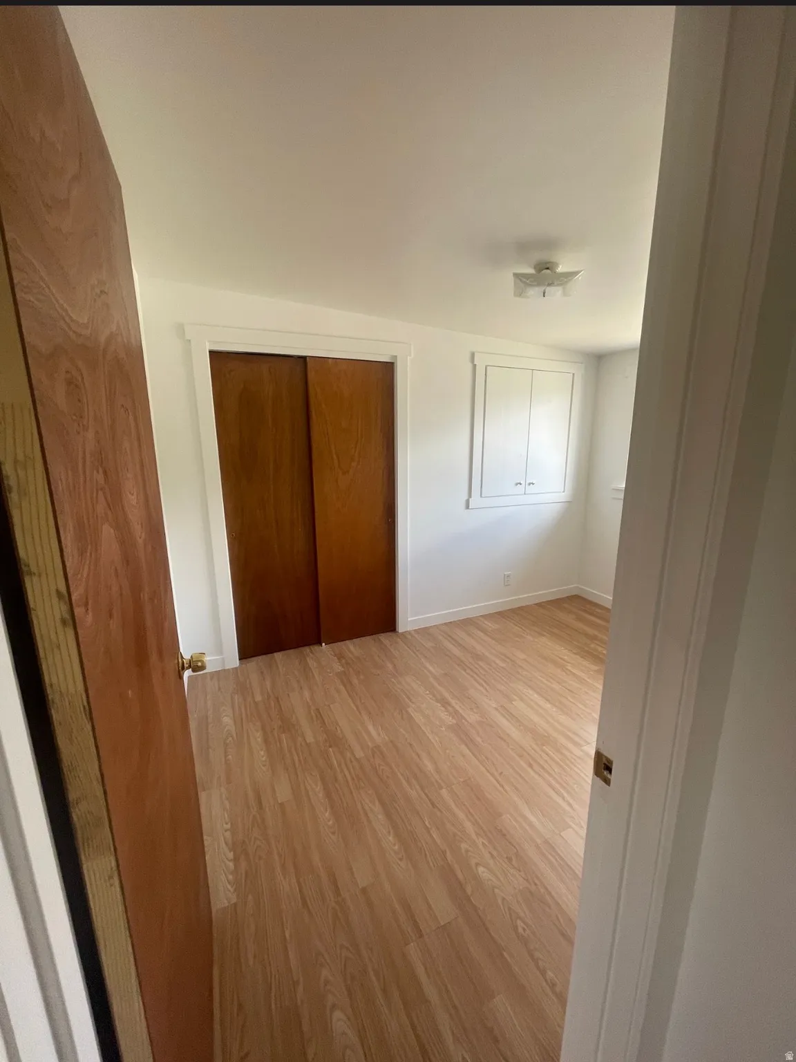 Bedroom featuring wood-finish flooring, a built-in closet with sliding wood doors, a built-in wall cabinet, and a flush-mount ceiling light fixture