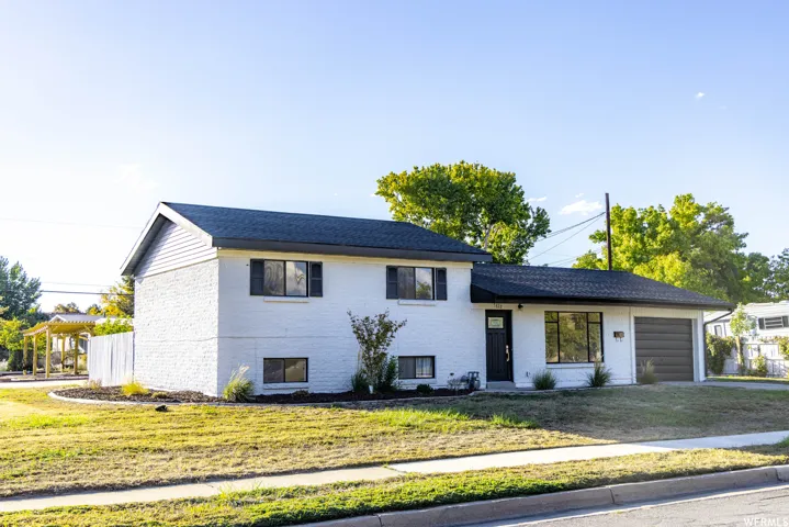 White brick exterior with dark trim accents and a black composite shingle roof