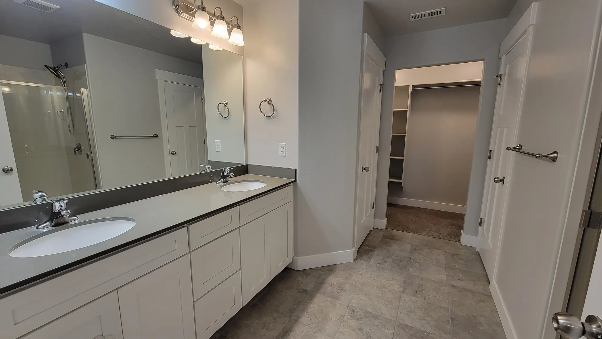 Dual vanity with light cabinetry, undermount sinks, and a dark countertop