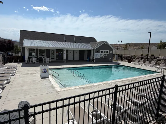 Outdoor swimming pool featuring a concrete deck and surrounding black metal fencing