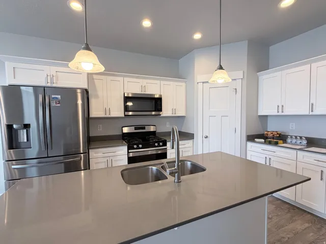 Modern kitchen featuring a central island with an undermount double-basin sink and a gooseneck faucet