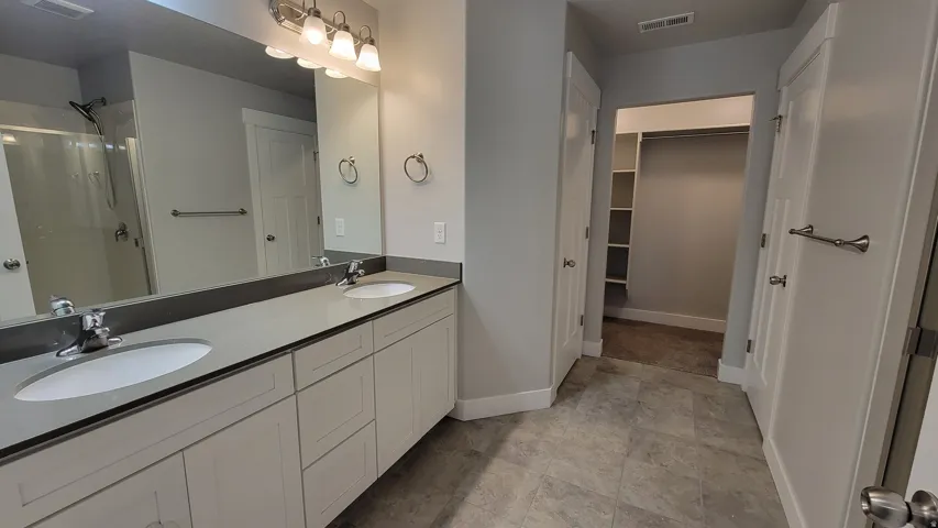 Dual vanity with light cabinetry, undermount sinks, and a dark countertop
