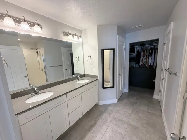 Dual vanity with undermount sinks, light gray countertops, and white cabinetry