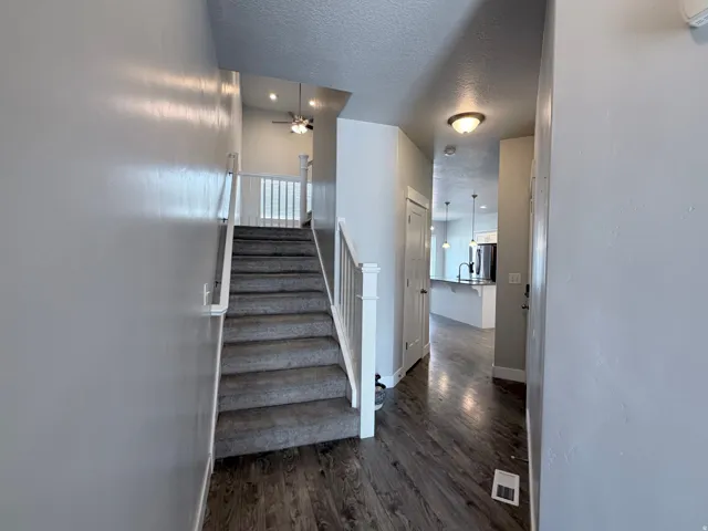 Entryway featuring wood-finish flooring, a carpeted staircase with white banister, and recessed lighting
