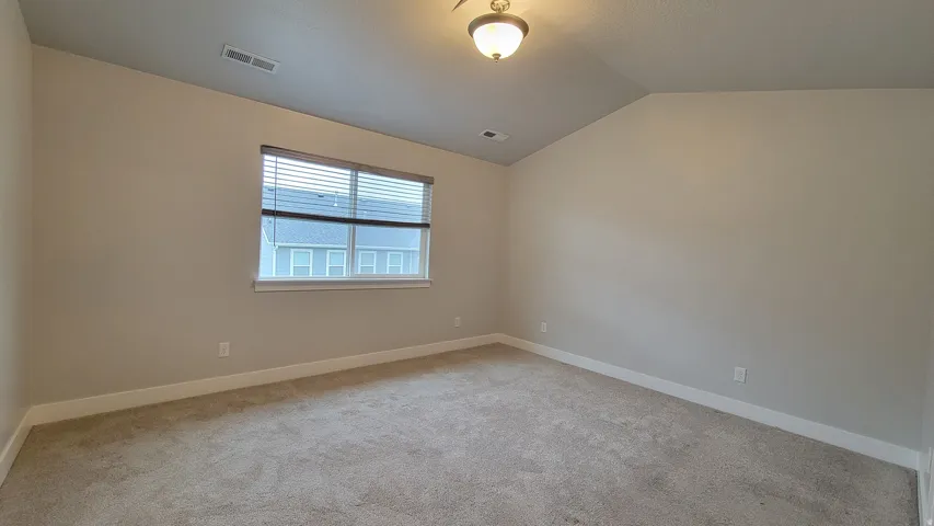 Carpeted room featuring neutral wall paint, white baseboards, a window with horizontal blinds, and a flush mount ceiling light fixture