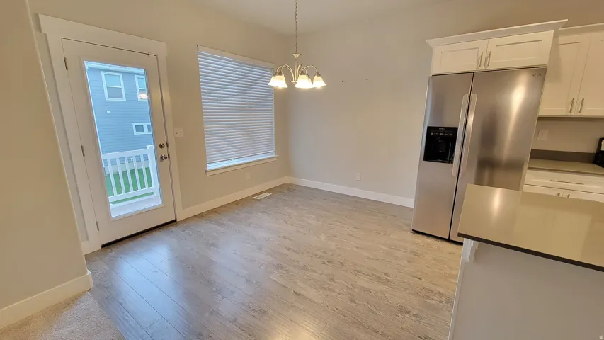 Dining area featuring wood-finish flooring, a window with horizontal blinds, and a glass-paneled door