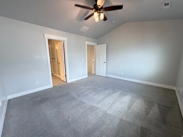 Spacious room featuring vaulted ceilings, light gray wall paint, and gray carpeting