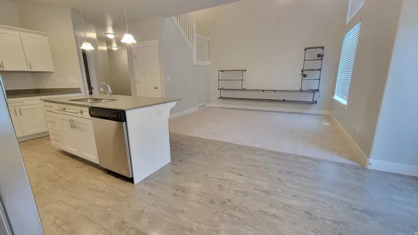 Kitchen island with an undermount sink, stainless steel dishwasher, and pendant lighting
