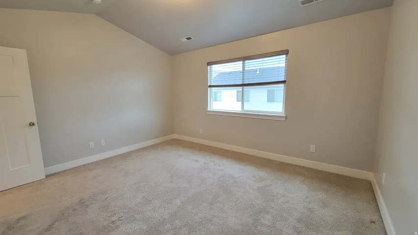 Carpeted interior space featuring a window with blinds, white trim, and a white interior door