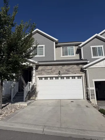 Two-story residence featuring a stone and siding exterior, an attached two-car garage, and a concrete driveway