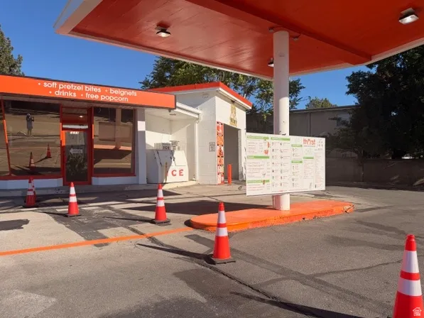 Commercial structure featuring a prominent orange canopy and a storefront with tinted windows