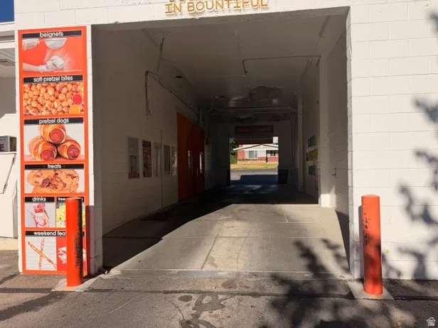 Drive-through entrance featuring a white block exterior, a paved access ramp, and orange safety bollards