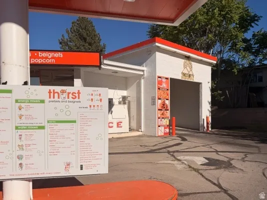 Commercial building featuring a white facade with orange trim, a prominent menu board, and a drive-through canopy