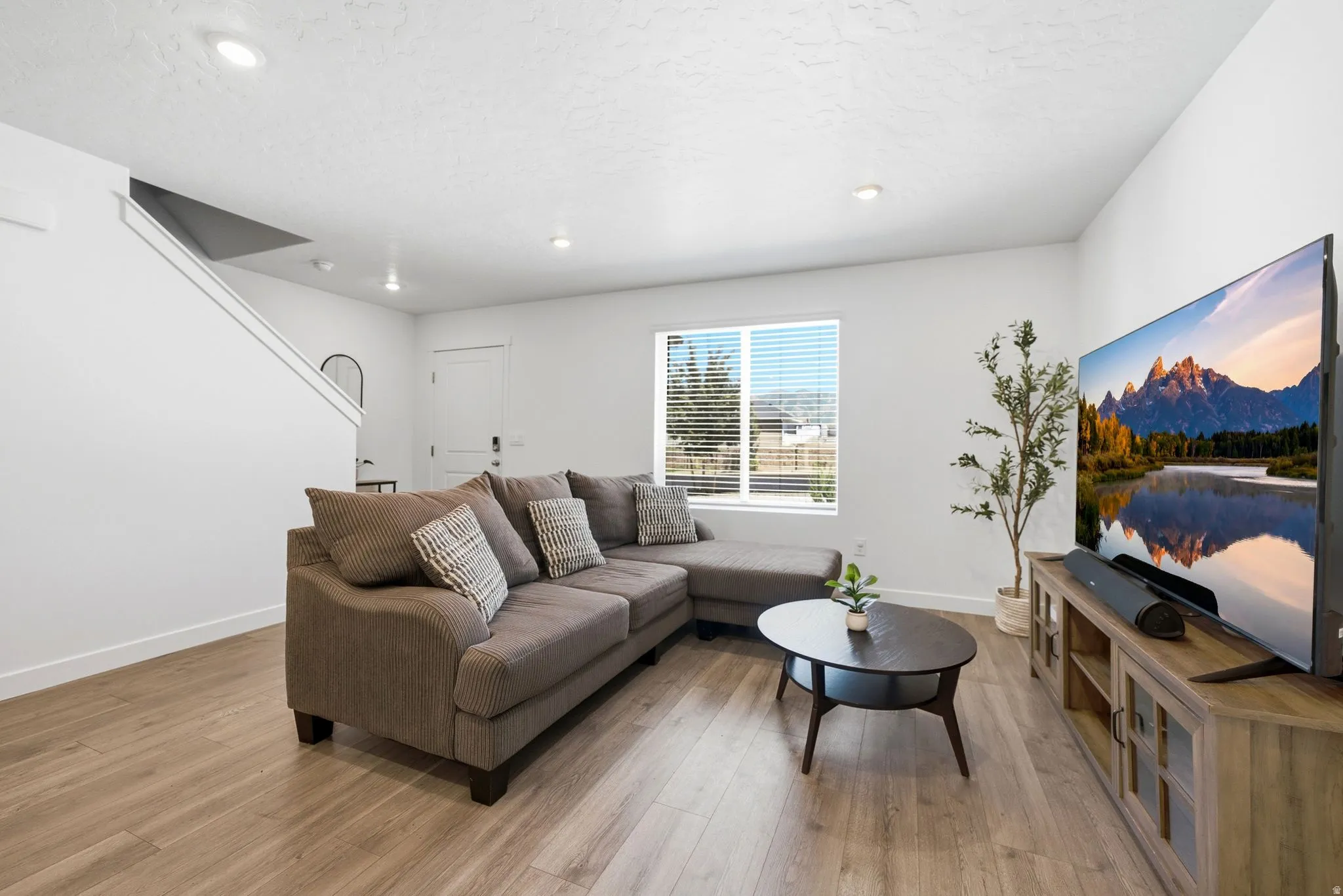 Open concept living area featuring wood-finish flooring, recessed lighting, and a neutral color palette