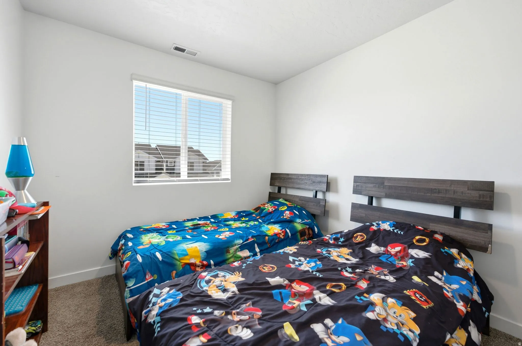 Bright interior room with white painted walls, a window featuring horizontal blinds, and neutral carpet flooring