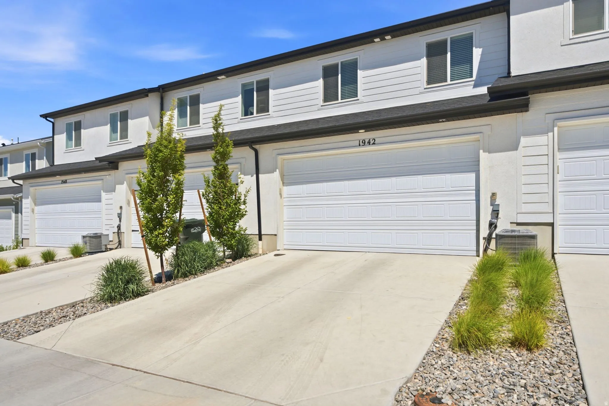 Modern townhome exterior featuring clean architectural lines, light-toned siding, and a contrasting dark roof
