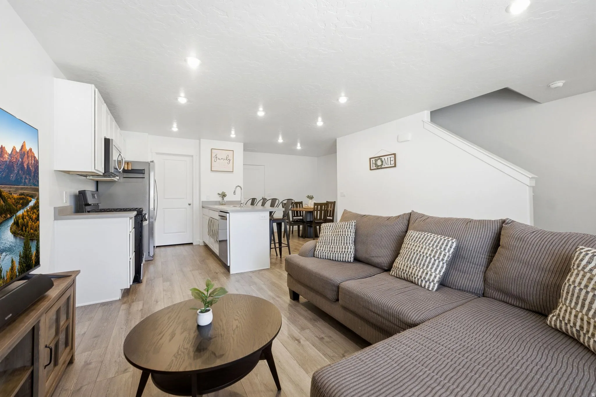 Open-concept living space with wood-finish flooring, recessed lighting, and a neutral color palette
