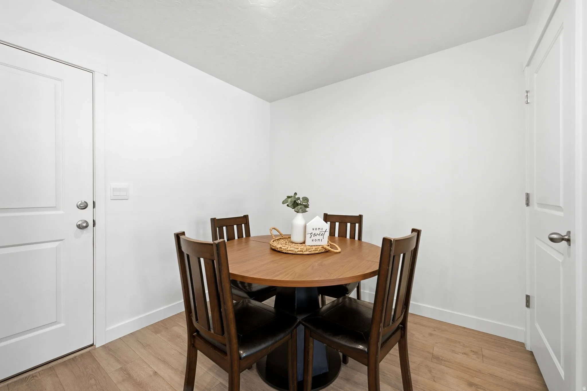 Dining area featuring wood-finish flooring, white walls, and bright overhead lighting