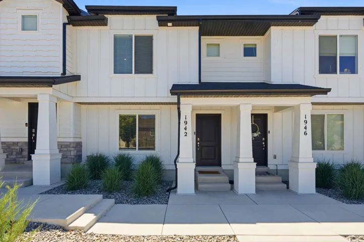 Contemporary townhome exterior with white board and batten siding, black trim, and a covered porch entry