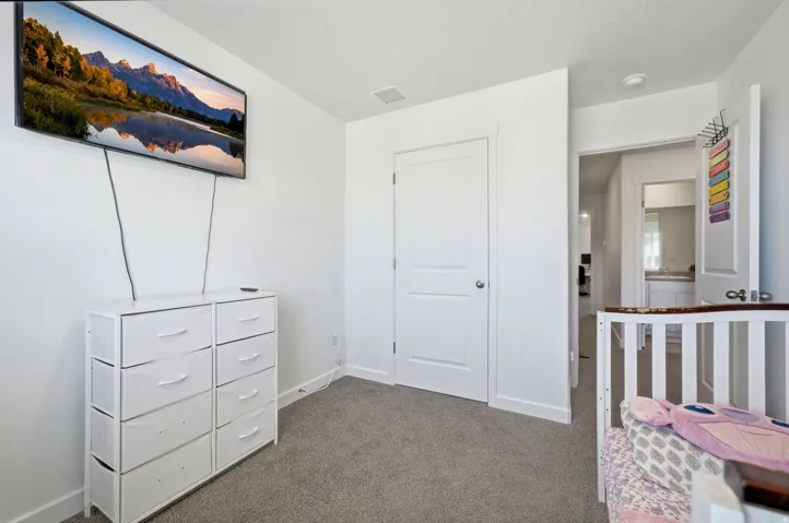 Carpeted room with a white door featuring a brushed nickel knob