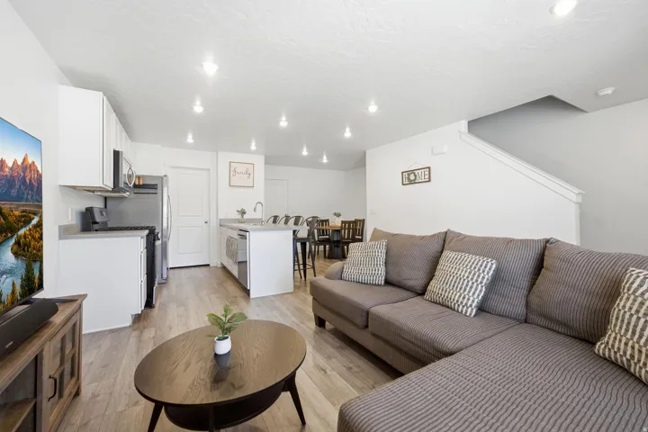Open-concept living space with wood-finish flooring, recessed lighting, and a neutral color palette
