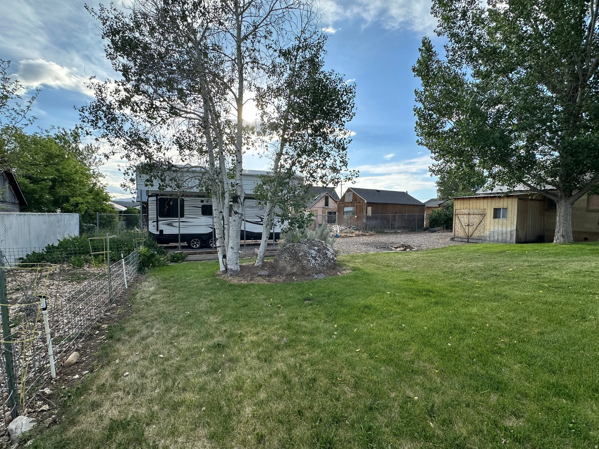 Expansive green lawn with mature trees and a fenced area