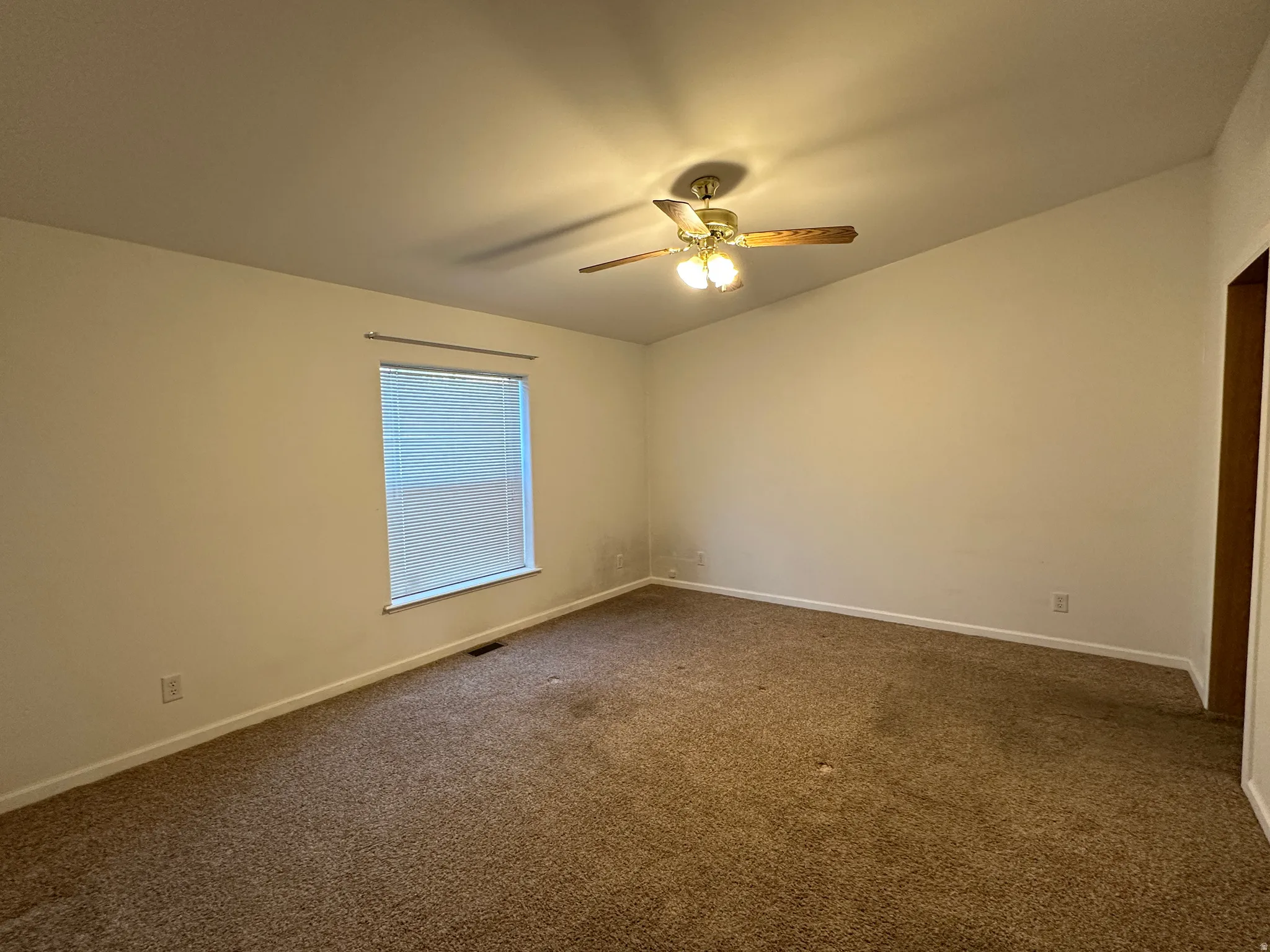 Carpeted room featuring a sloped ceiling and a window with blinds