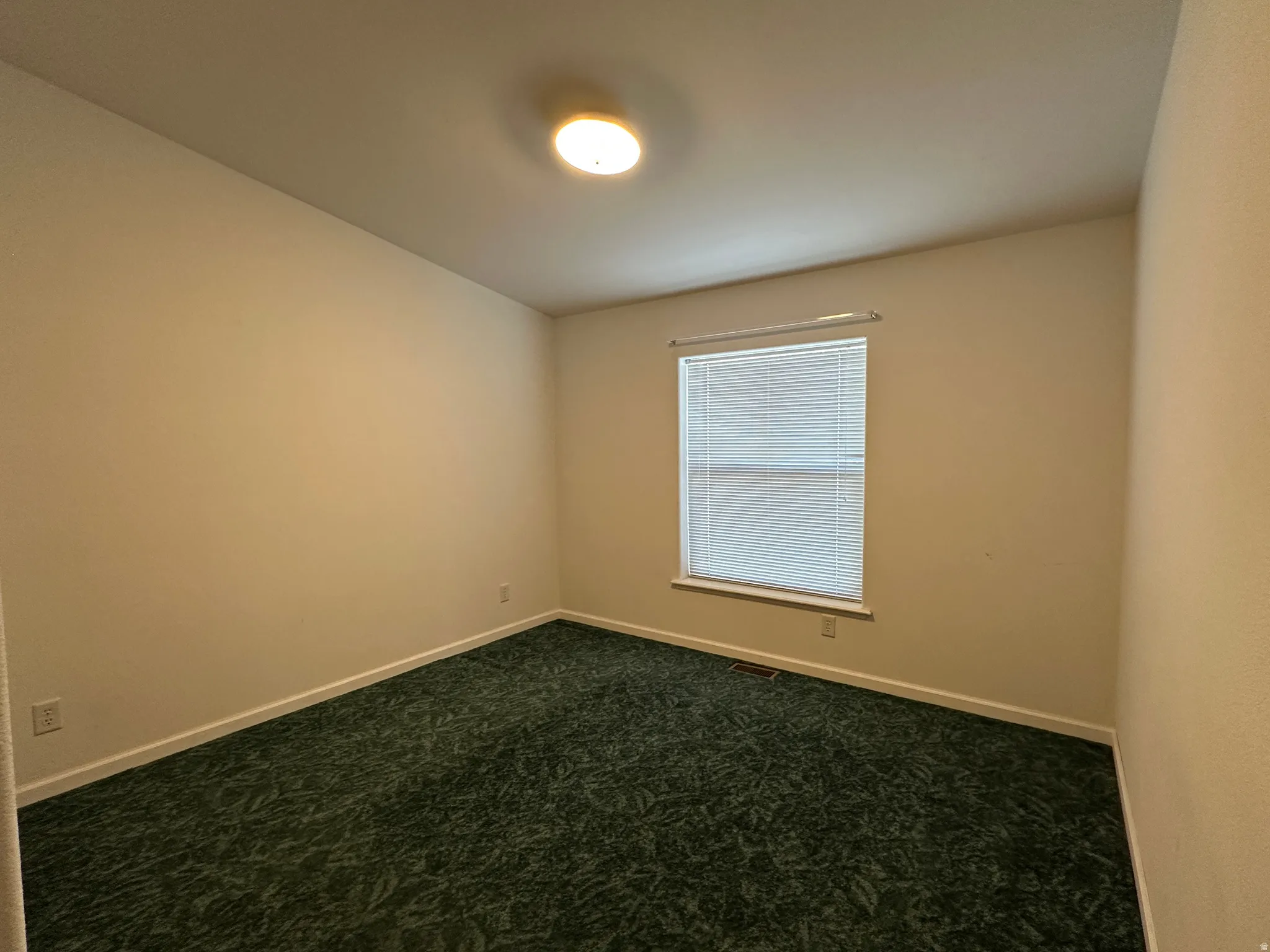 Neutral tone wall paint with a single window featuring horizontal blinds