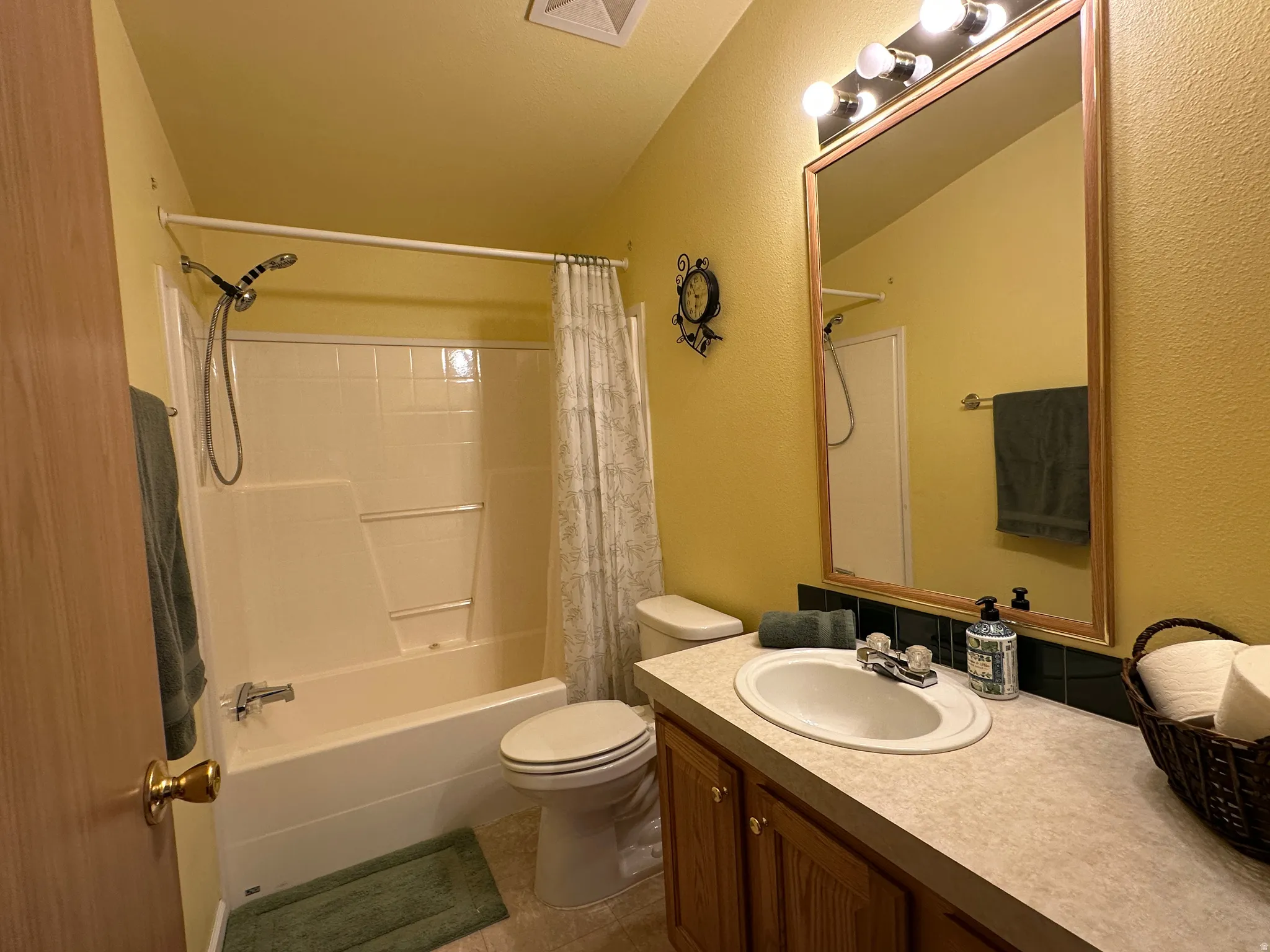Full bathroom featuring a shower/tub combination, vanity with wood-finish cabinetry, and an illuminated mirror
