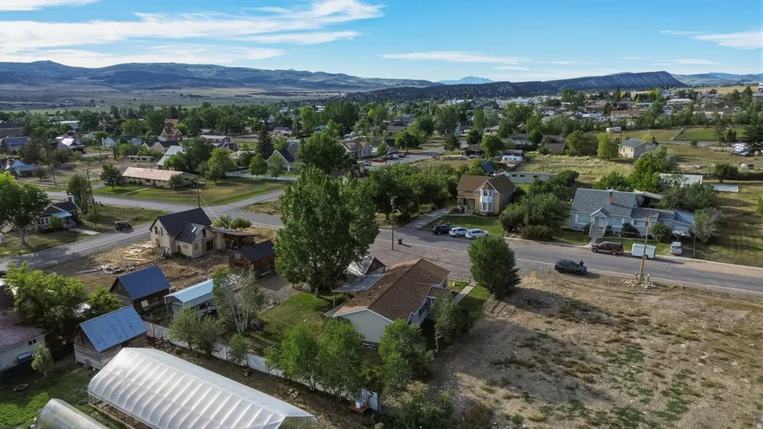 Aerial perspective of a neighborhood featuring residential structures, mature trees, and a distant mountain range