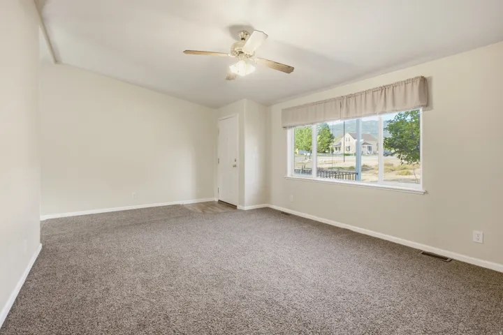 Spacious room featuring vaulted ceilings and a large window with white trim