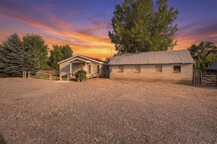 Gravel foreground with mature evergreen and deciduous trees, shop-shed