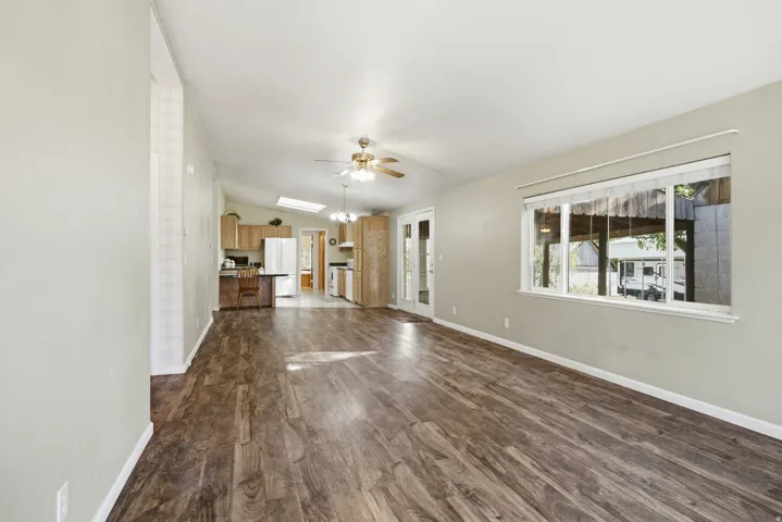 Spacious living area featuring wood-finish flooring, vaulted ceilings, and a large window